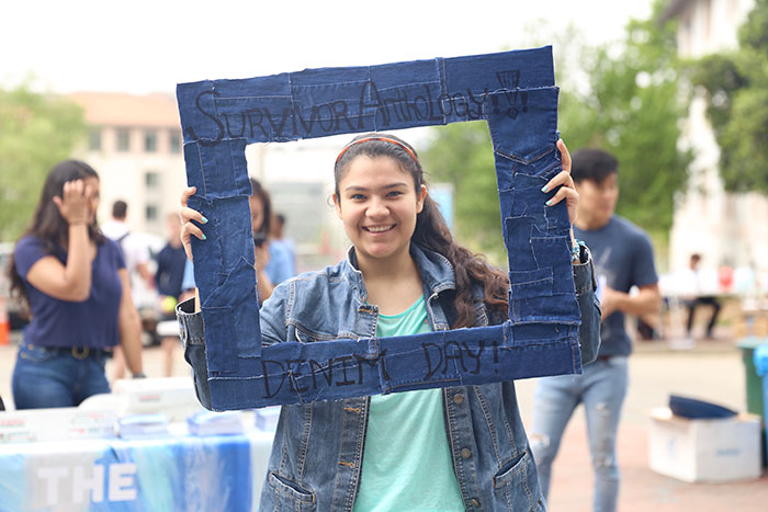 A student holds up a denim frame to pose for a photo to post on social media.