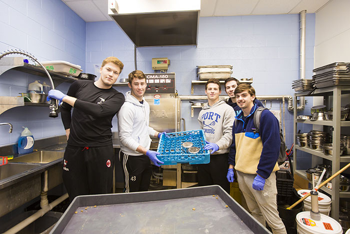 A group of students wear gloves and clean various items in the facility at LifeLine Animal Project