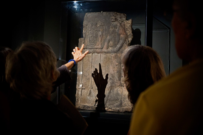 Participants look at ancient art under light.