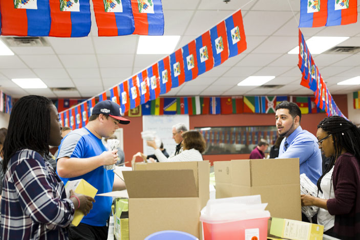 Several volunteers talk while working to package multiple cardboard boxes.