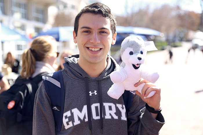 A student in an Emory sweatshirt holds up the toy animal he made.