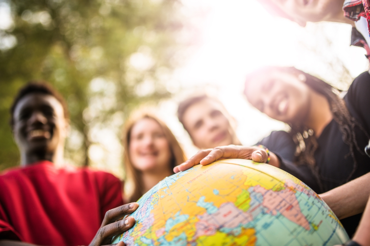 group of young adults with their hands on a globe