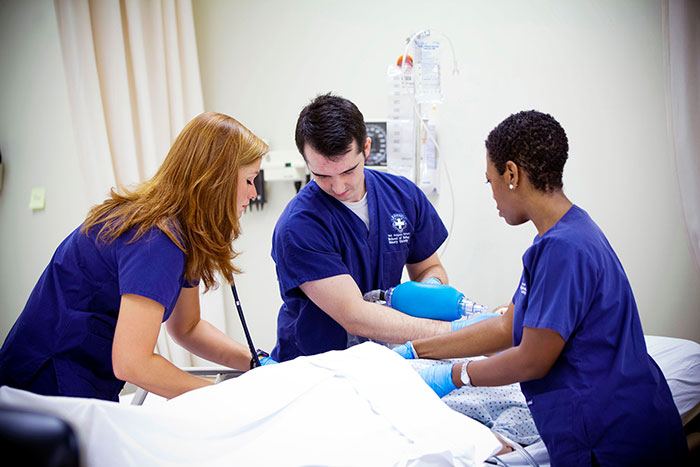 Three nursing students at the Nell Hodgson WoodThree nursing students at the Nell Hodgson Woodruff School of Nursing practice caring for a patient in this 2012 photo.ruff School of Nursing practice caring for a patient in this 2012 photo. 