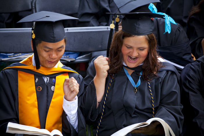 Two graduates see their names in the Commencement program. 