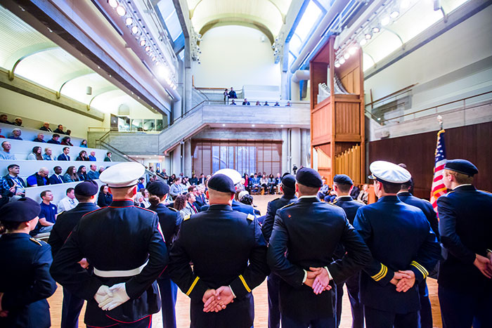 In a view from behind, a group of military service members stand at ease in the Cannon Chapel