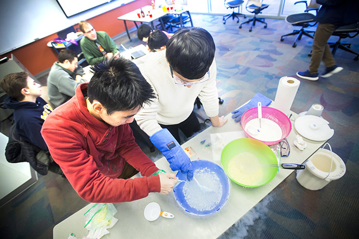 Students work with various white liquids in bowls in a chemistry class