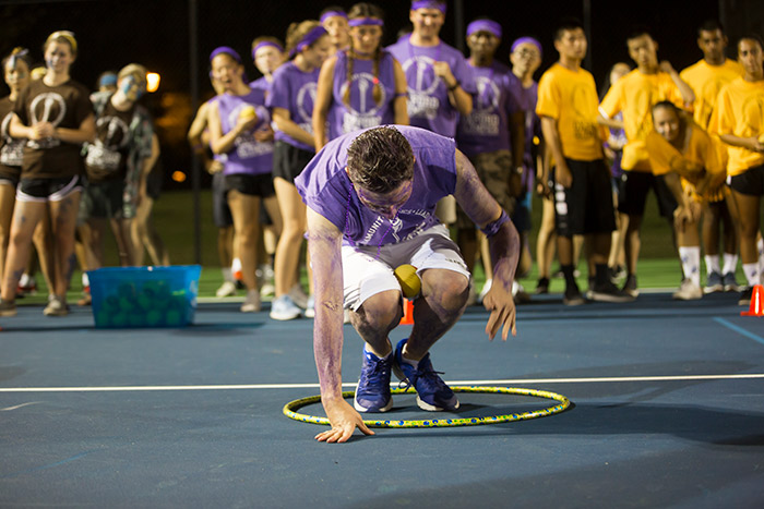 An Oxford College student wearing purple and yellow for his team stands in a hula hoop.