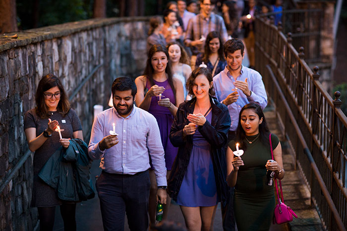 Students cross the Emory bridge holding candles over Houston Mill Road to the Miller-Ward Alumni House.
