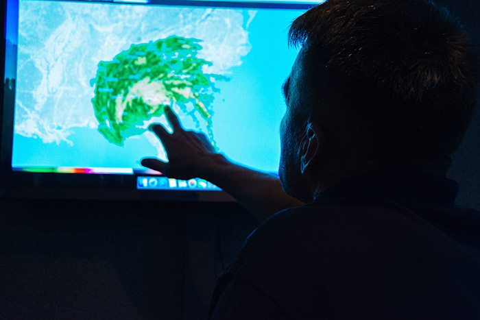 A CEPAR staff member points at the weather radar on a big screen.