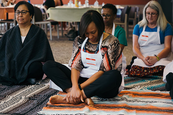 Staff members sit on blankets as they are guided through a relaxation exercise.