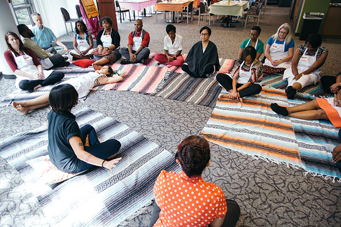 Staff members sit and lay on blankets as they are guided through a relaxation exercise.