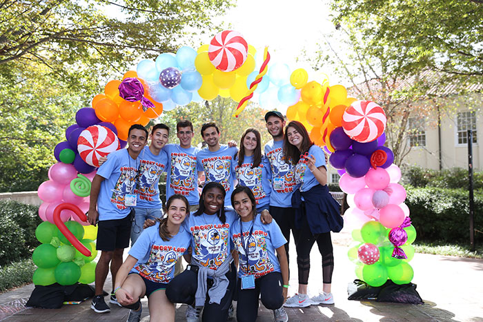 Students pose under a candy-themed balloon display.