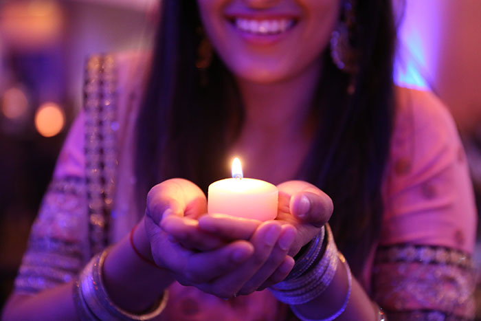 A student smiles as she holds a small candle.