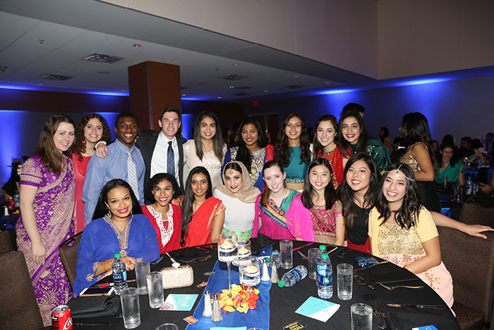 A diverse group of students pose, wearing colorful saris at the Diwali celebration.