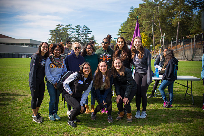 A group of students pose in front of a volunteer table at Emory Cares International Day of Service.