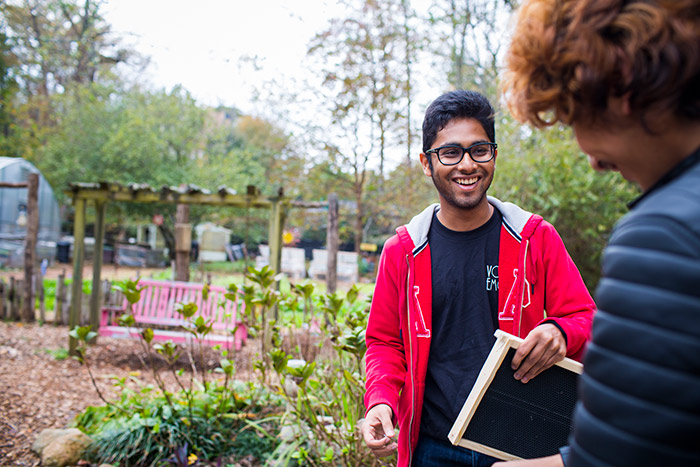 Two students share a smile as they work at the community gardens. 