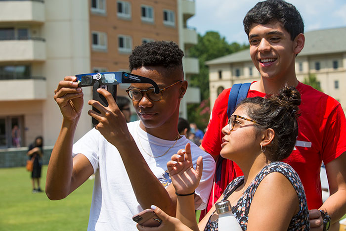 A student takes a picture through his eclipse glasses.