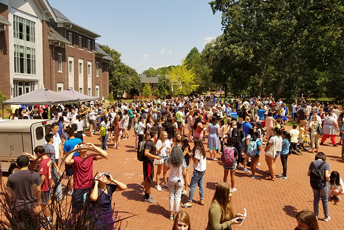 Dozens of students stand outside to observe the eclipse.