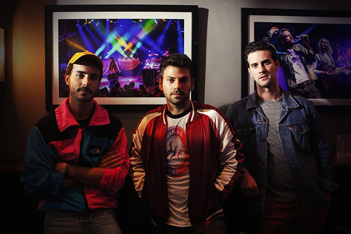 Adam Hoffman, Matt Lipkins and Scott Tyler pose for a picture together in front of a wall of art.
