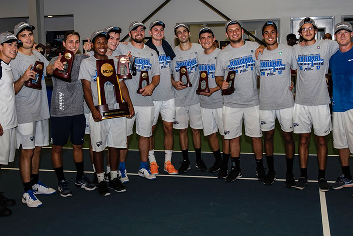 The Emory men's tennis team stands together, big smiles on their faces, after winning the NCAA Division III Championship.