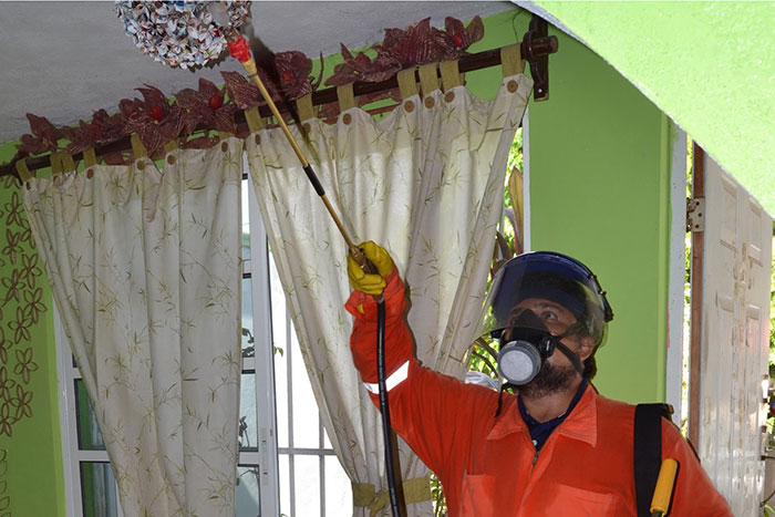 A research technician donning PPE sprays the ceiling of a home in Merida, Mexico.