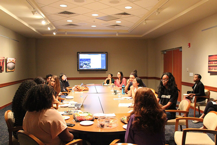 The class sits around a large table, discussing the exhibit.