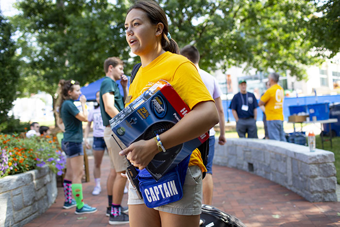 A student volunteer carries various items into a dormitory to help a student move in