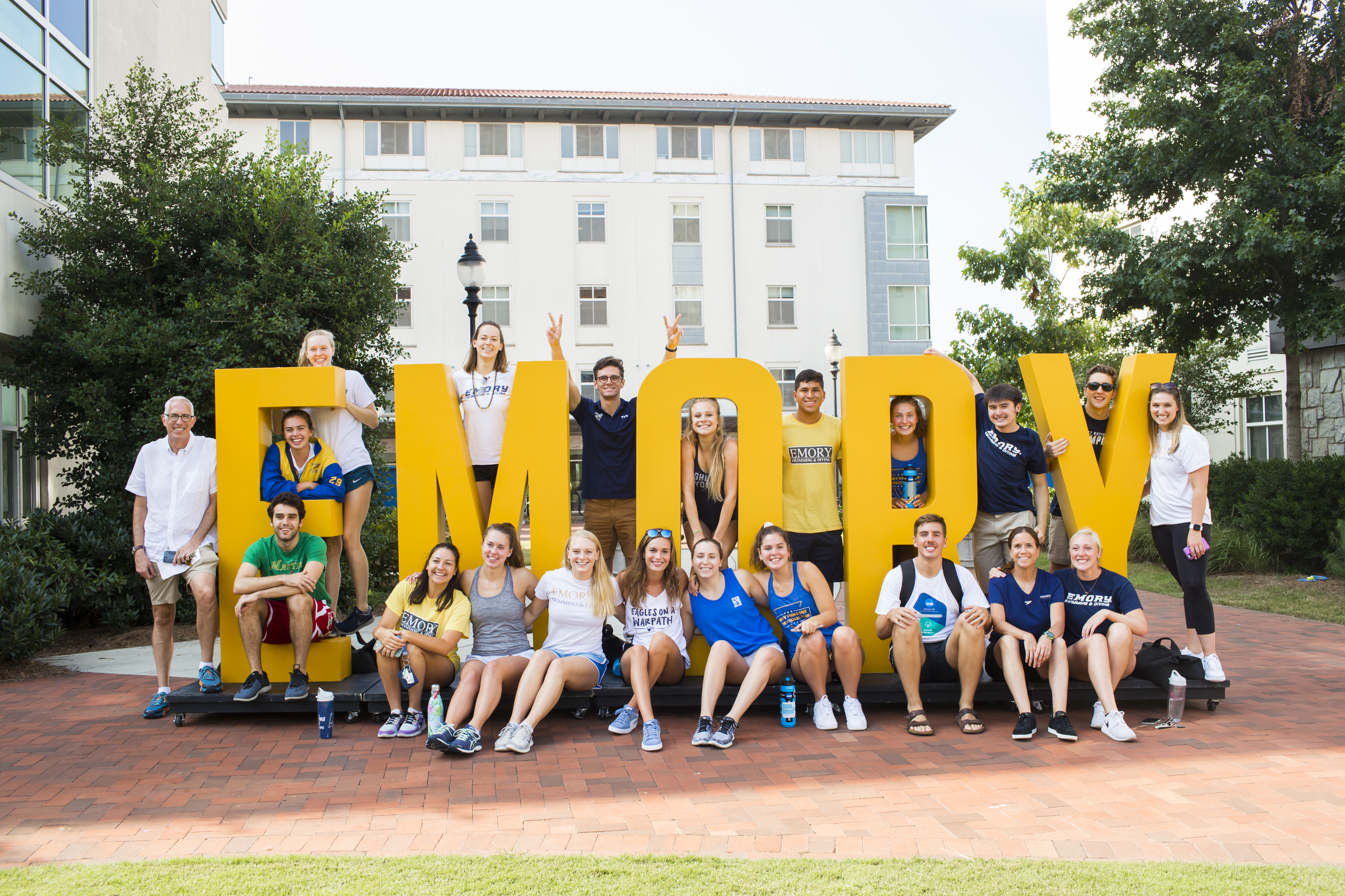 Several students and parents pose around a sculpture that says the word Emory
