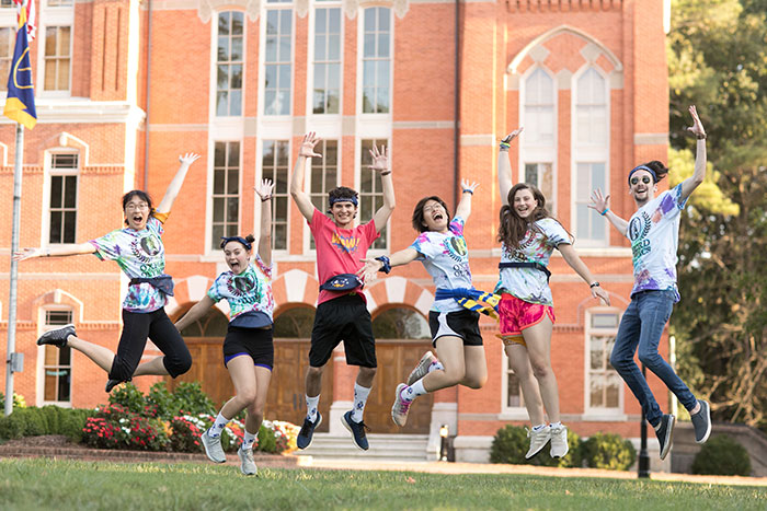 Students wearing various Oxford Olympics t-shirts jump synchronously in the quad