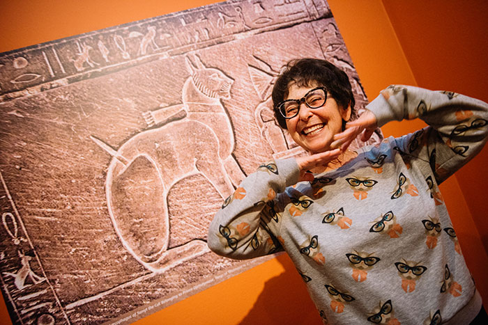 An exhibition attendee poses with a stone carving of a cat