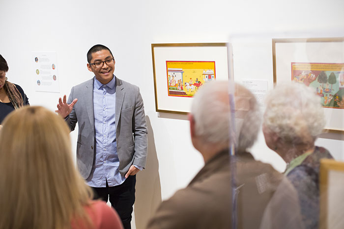 A young man speaks to a crowd about a particular work of art on display