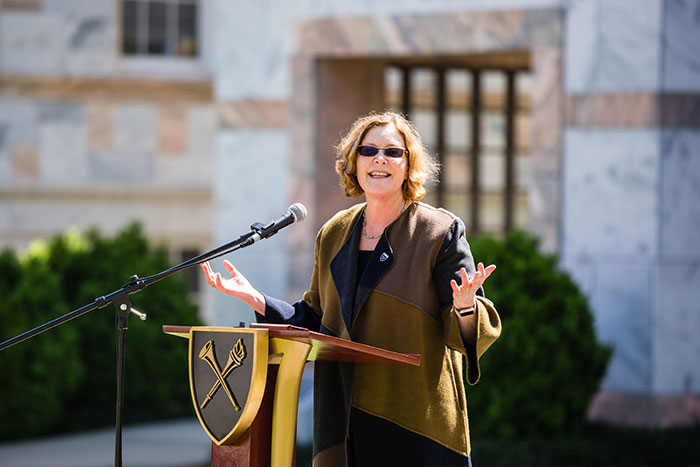 Emory President Claire E. Sterk speaks at a podium at the first Conversations on the Quad