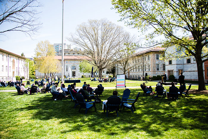 A large group including dozens of Emory community members sit in blue lawn chairs at the first Conversations on the Quad