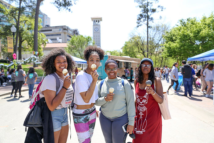 Four Emory students hold up ice cream cones they got at a Dooley's Week event