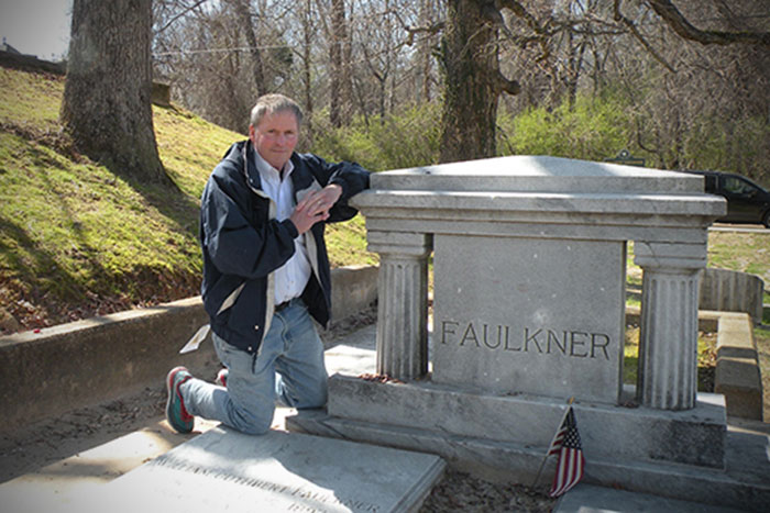 Clyde Partin Jr., a physician and professor in the Emory School of Medicine, poses at Faulkner¿s grave.