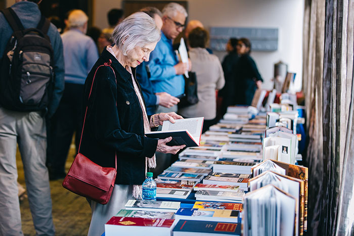 Participants look at faculty books on display at a table