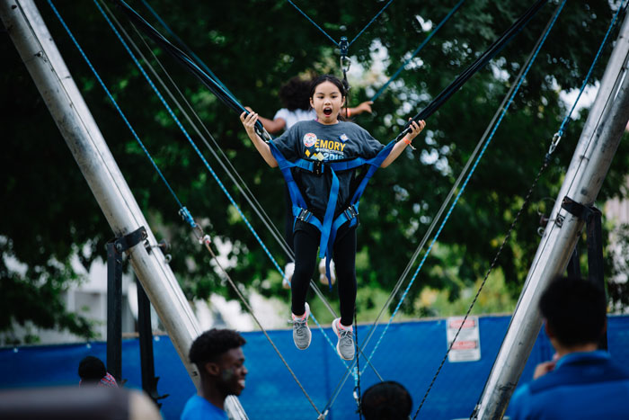 A little girl is suspended by bungee cords as she jumps on a trampoline at the Homecoming Festival