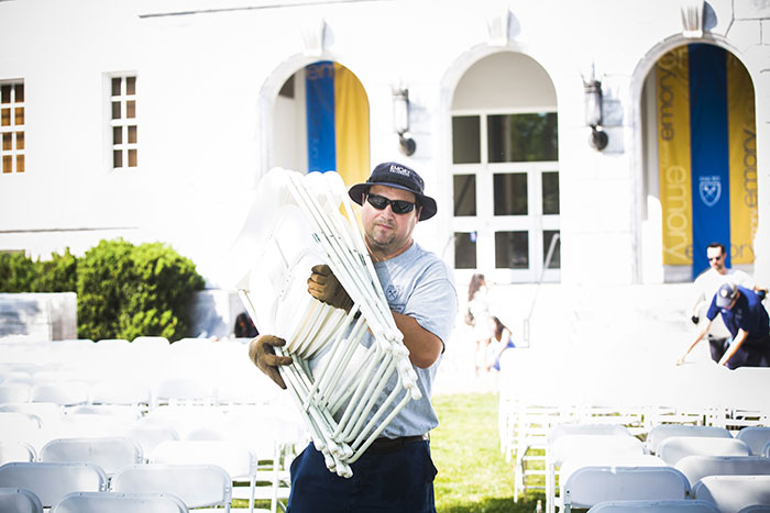 An Emory employee carries a stack of chairs