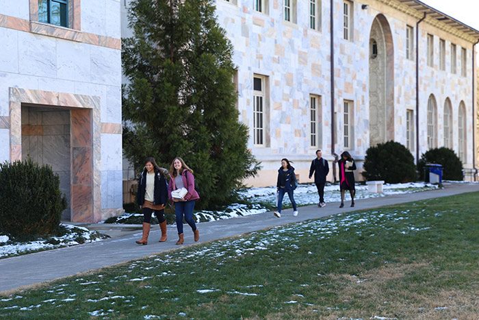 Four students and a professor walk across campus