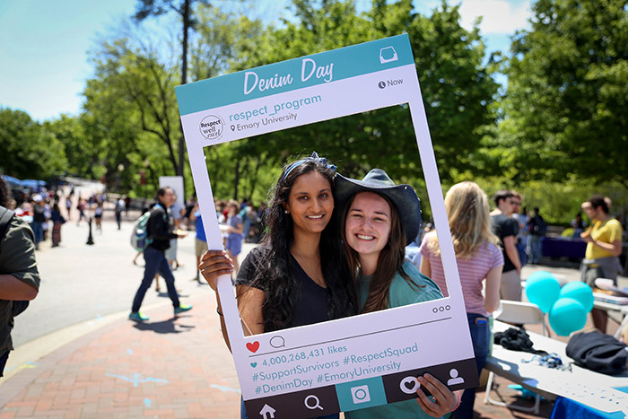 Two Emory students pose in a frame shaped like an Instagram post for Denim Day.