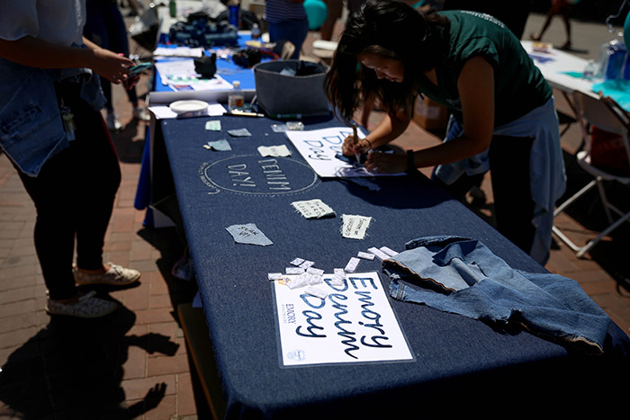 A student writes on a piece of paper at an Emory Denim Day table.