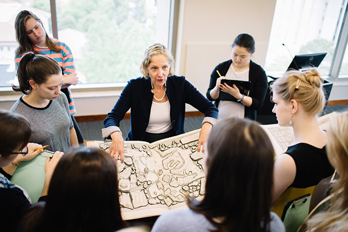 Art history professor Sarah McPhee and graduate student and Mellon Fellow Abbey Hafer point to details on an etching while speaking to a class.