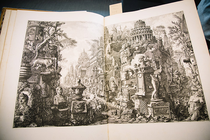 A close-up of a Piranesi etching, showcasing a black and white sketch in a book showcasing ancient Roman statues and buildings