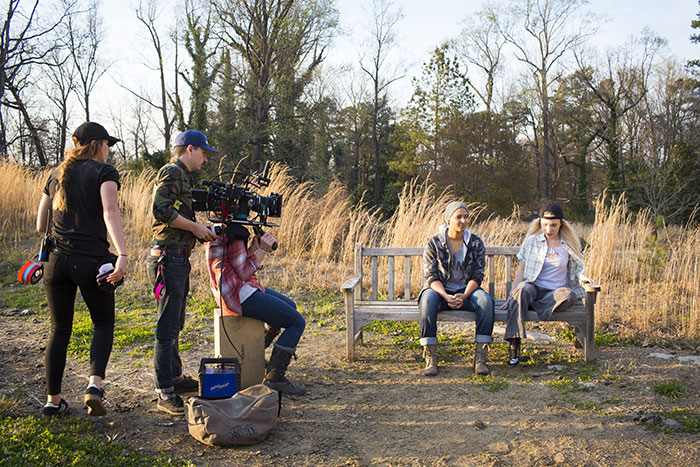 Emory students work with a professional film crew to film an outside scene on a bench near Emory's campus.