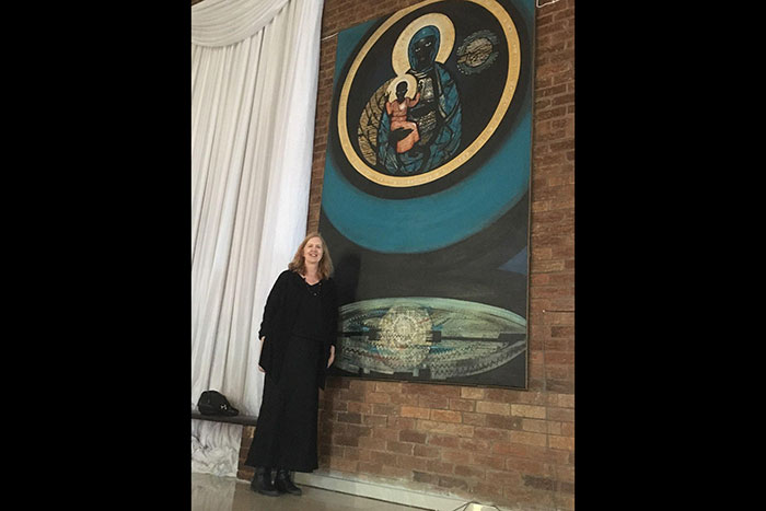 Pamela Scully poses in front of her father's painting, "The Madonna and Child of Soweto."