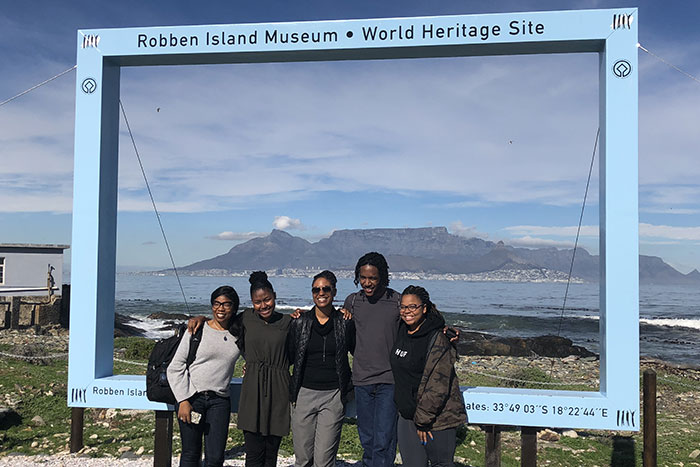 Three trip participants pose in front of a life-size photo frame intended for visitors to take photos in front of