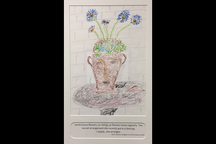 A drawing of flowers in a jug by Sandra Haisten. The caption on the image reads: "Sandra loves flowers, so I bring cut flowers home regularly. This was an arrangement she recently put in a face jug. I supply...she arranges. - Harry Haisten, Caregiver and Sandra Haisten, Artist"
