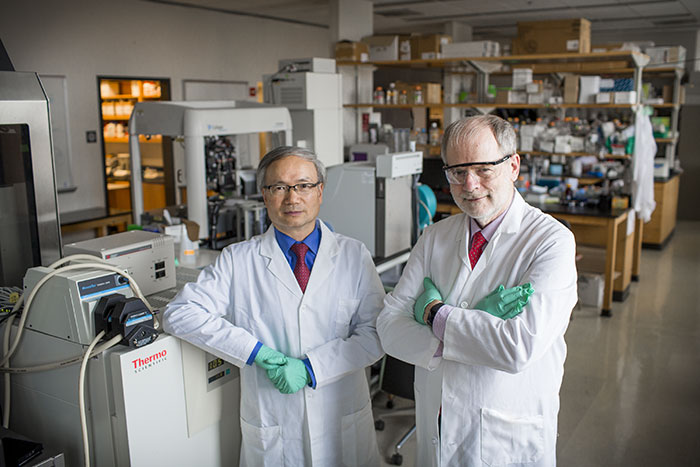 Haian Fu and Huw Davies pose in a laboratory wearing lab coats