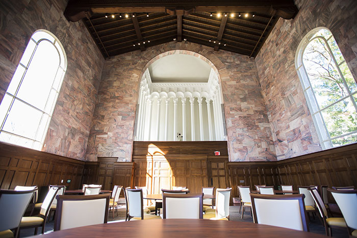 An interior view of Convocation Hal showing the restored state of the original chapel, highlighting a multi-story arch cutout reaching the exposed beams in the ceiling
