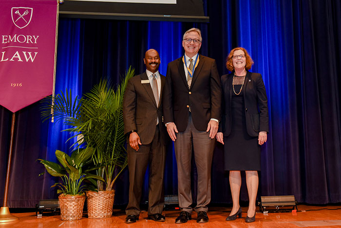 David Adelman stands between Dean Hughes and Emory President Claire E. Sterk on a stage.